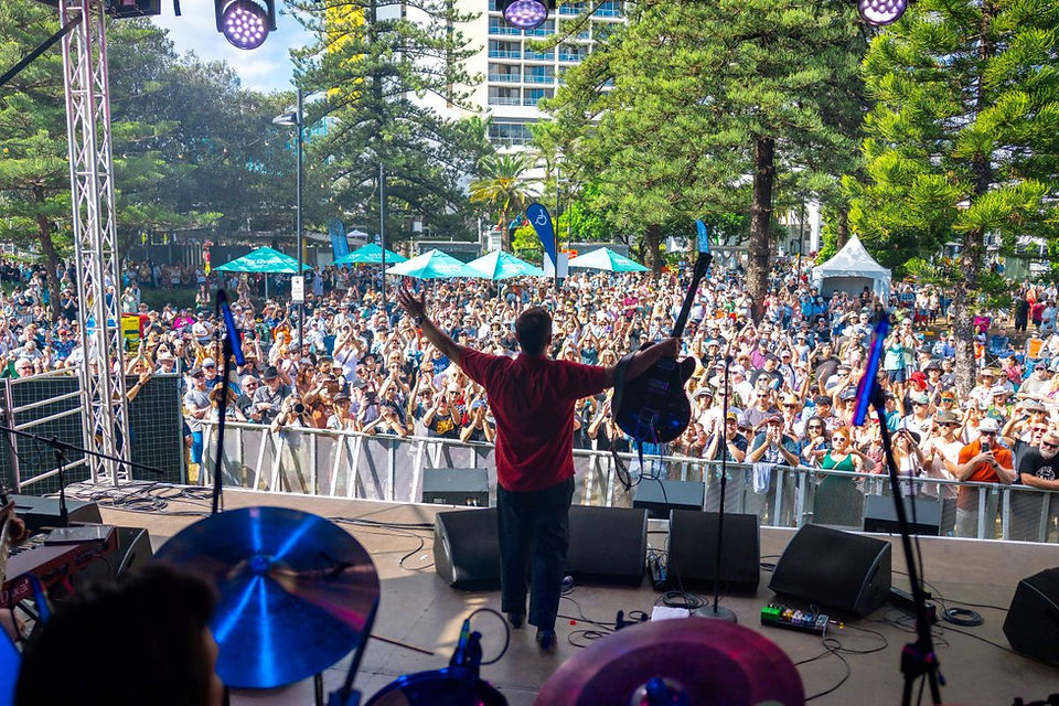 Performer on stage with arms raised at Blues on Broadbeach 2025 — accommodation nearby at Burleigh Gold Coast Motel