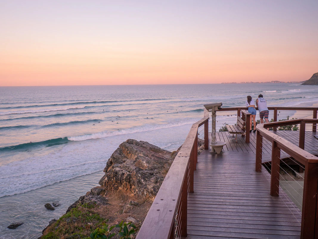 Couple watching sunset from North Burleigh Lookout deck overlooking ocean and Surfers Paradise