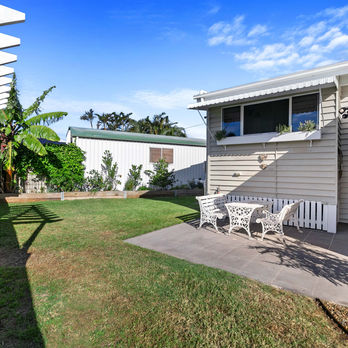 backyard of queenslander house with back patio and outdoor setting. red banana tree and garden bed with fruits and vegetables