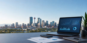 Laptop, calculator and printed reports on a desk with Calgary skyline in the background