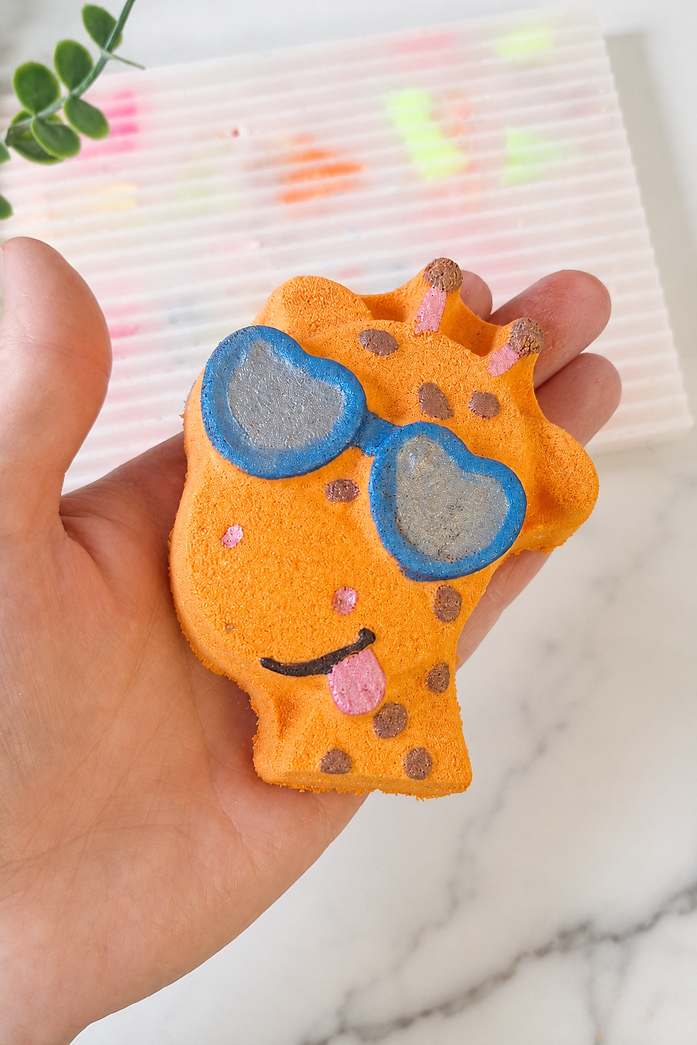 Cool Giraffe kids’ bath bomb held in hand to show its size and hand-painted details