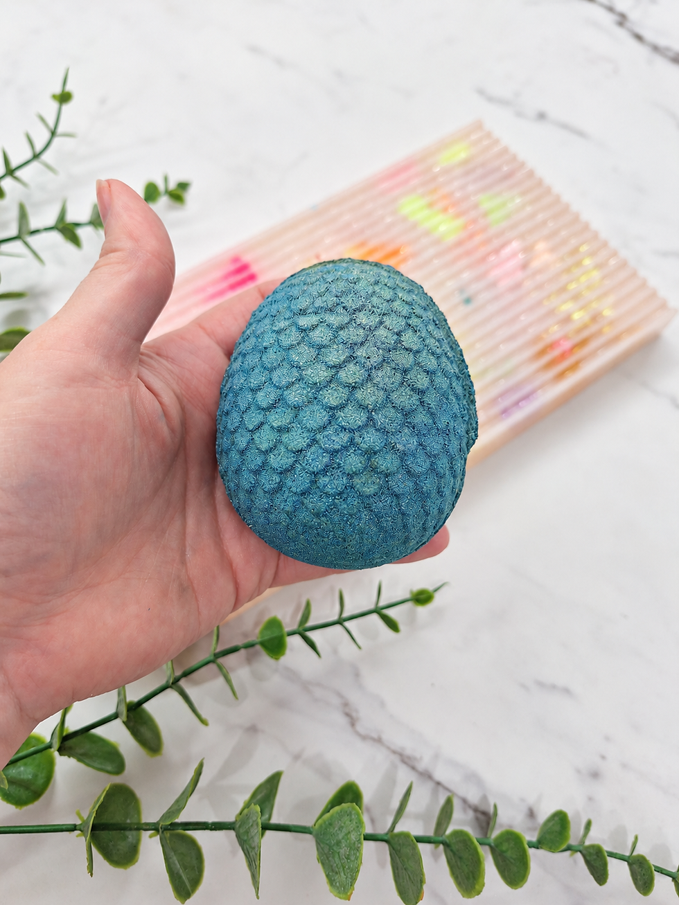 250g dinosaur egg bath bomb held in a hand to show its size and scale texture