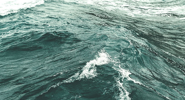 Textured background with a rich blue-green sea in close-up. Waves in the dark pre-storm se