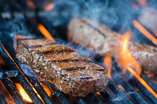 a chargrilled steak sizzling over hot flames