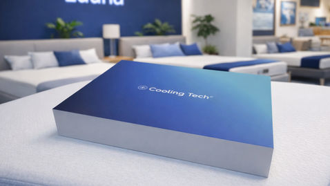 Caja de exhibición Cooling Tech colocada sobre colchón Luuna en tienda retail, diseñada para comunicación de producto en punto de venta.