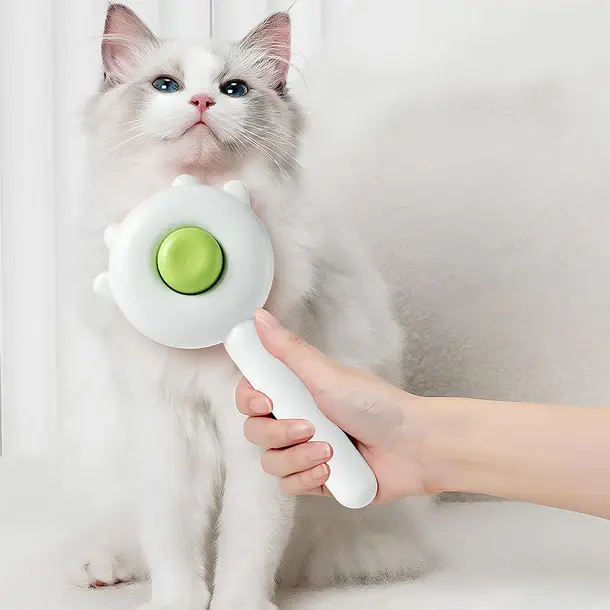 Thumbnail: White cat sitting next to green one-touch pet brush.