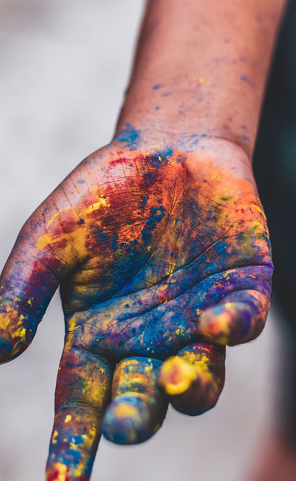 A hand covered in various colorful paints, symbolizing creativity and diversity, representing Pure Paint & Wallpaper’s wide