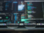 Glasses in focus over a blurred computer screen displaying colorful code. Blue and black visual details create a tech-focused mood.