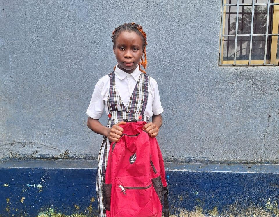 Cynthia, a fourth grader in Paynesville, Liberia, holds her new school backpack