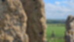 View through the weathered limestone slabs of the Whispering Knights at the Rollright Stones, looking across the Oxfordshire countryside.