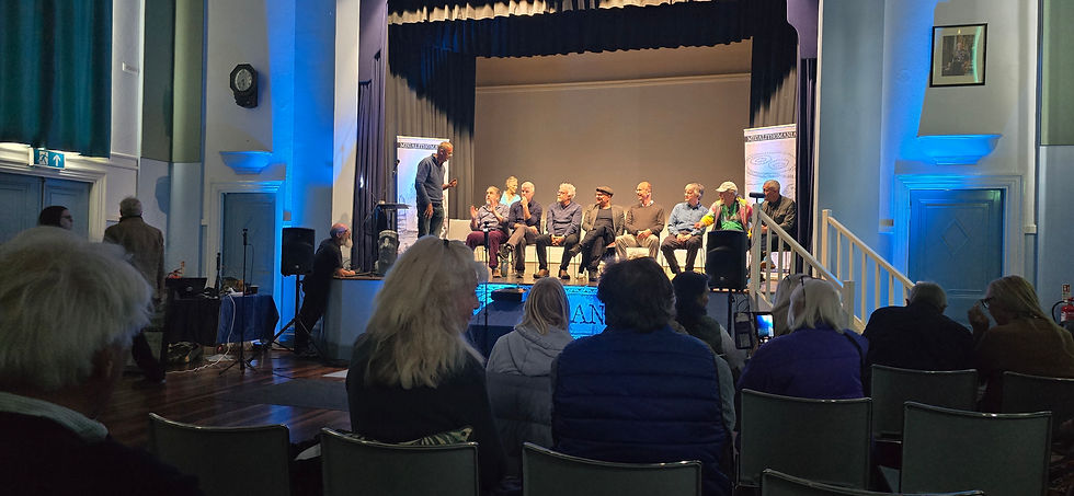 Megalithomania 2026 speakers forum on stage at Glastonbury Town Hall, with the audience watching from the hall.