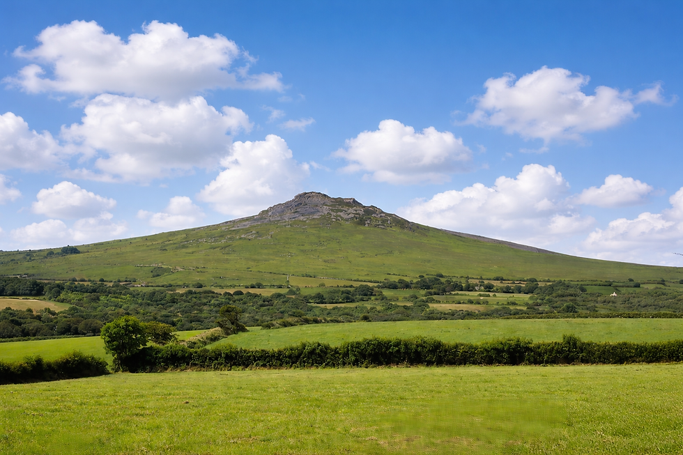 View of Carn Ingli showing a long green ridge rising to a rocky summit beneath a wide blue sky, emphasising the landscape’s vertebral form.