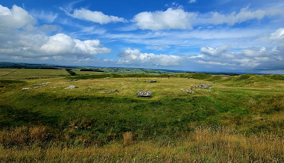 Arbor Low henge ditch and fallen stone circle on the limestone plateau with wide views across the Peak District landscape.