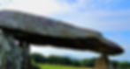 The Neolithic dolmen Pentre Ifan in Pembrokeshire, showing its long, capstone resting on uprights, with open pasture and distant hills of Carn Ingli beyond.