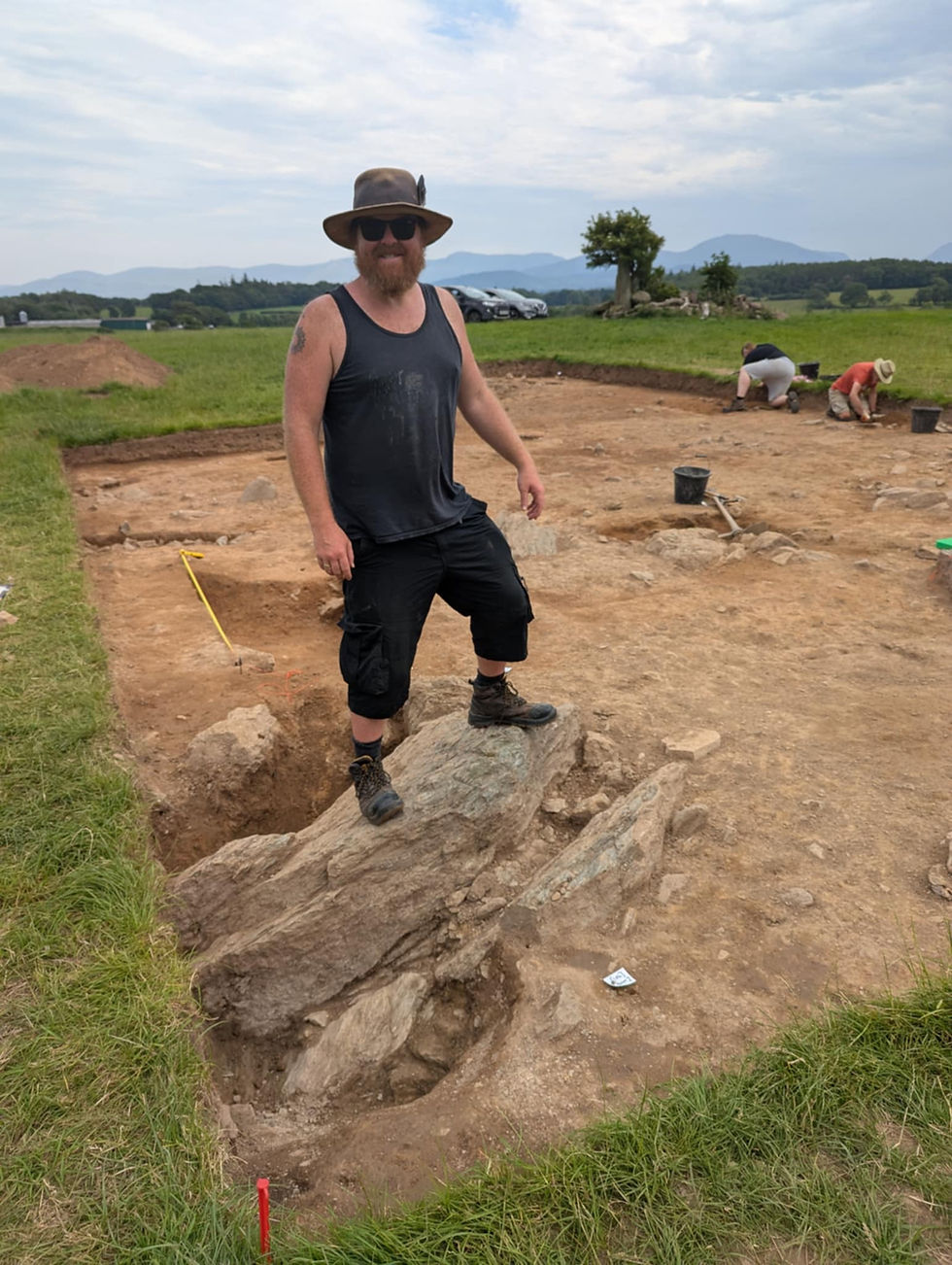 Dr. Mike Woods standing atop the newly uncovered Tyddyn Bach standing stone at the Bryn Celli Ddu excavation site on Anglesey.