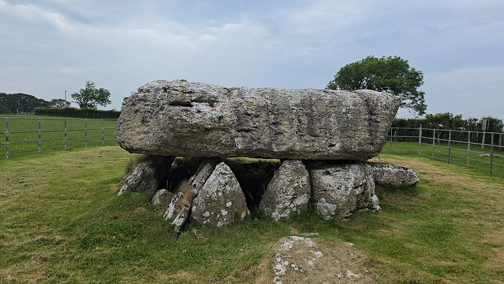 Front view of Lligwy Neolithic Burial Chamber on Anglesey, showing the massive limestone capstone resting above the surviving chamber stones and dark entrance.