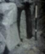 Excavation photograph of the narrow pillar stone in a recess at Barclodiad y Gawres, with an oyster shell found at its base.