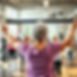 “Show a 60-year-old woman from the back inside a bright, modern fitness center, celebratin