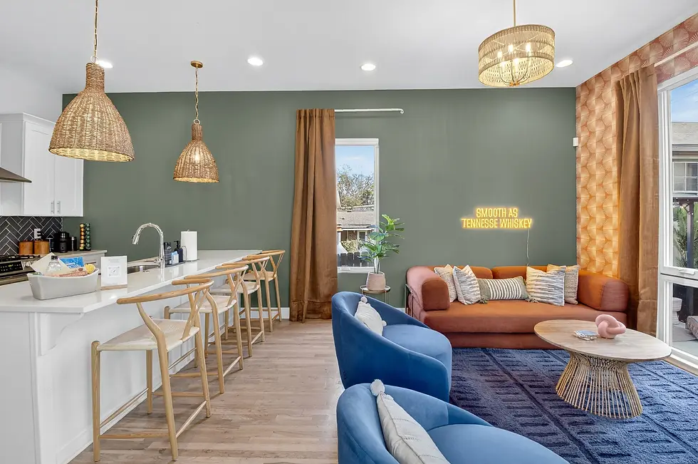 Modern open-concept living room in Nashville Airbnb with private parking, featuring sage green accent wall, orange sofa, and