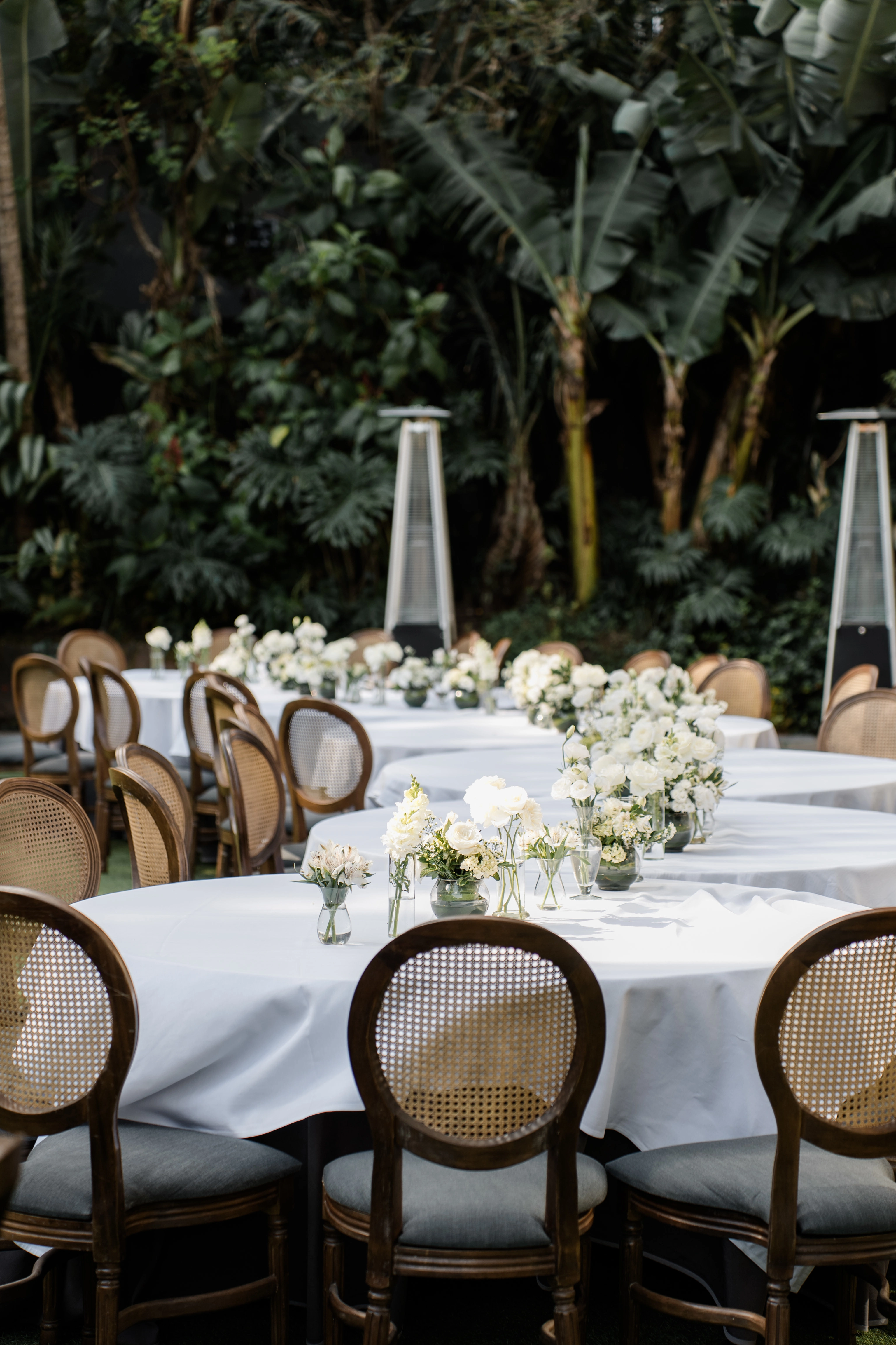 Recepção de casamento de alto padrão ao ar livre em frente a um edifício de luxo com arquitetura orgânica, fachada de madeira e vegetação vertical integrada.