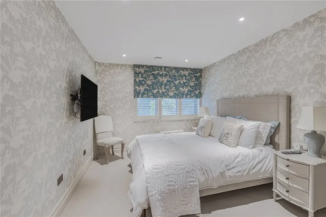 bedroom with tv and wallpapered wall