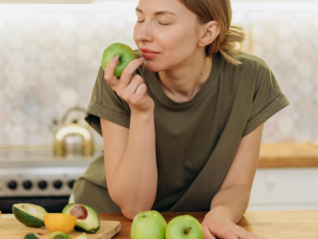 Woman eating an apple with eyes closed, practicing sensory awareness and mindful eating habits