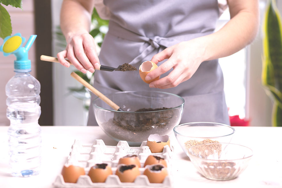 A person wearing an apron filling an empty egg shell with dirt.