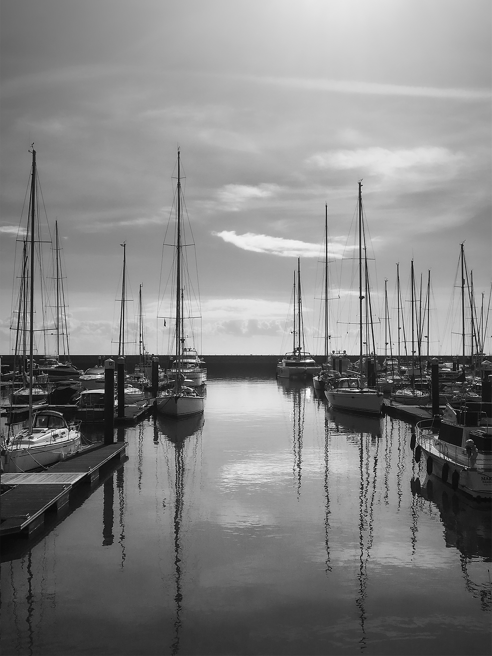 Fotografia de docas com barcos em contraluz em preto e branco