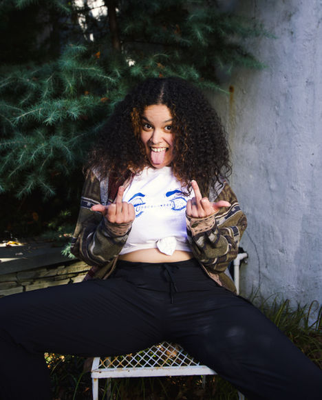 Francheska, with a Project Feel white shirt on, sticking their tongue out and