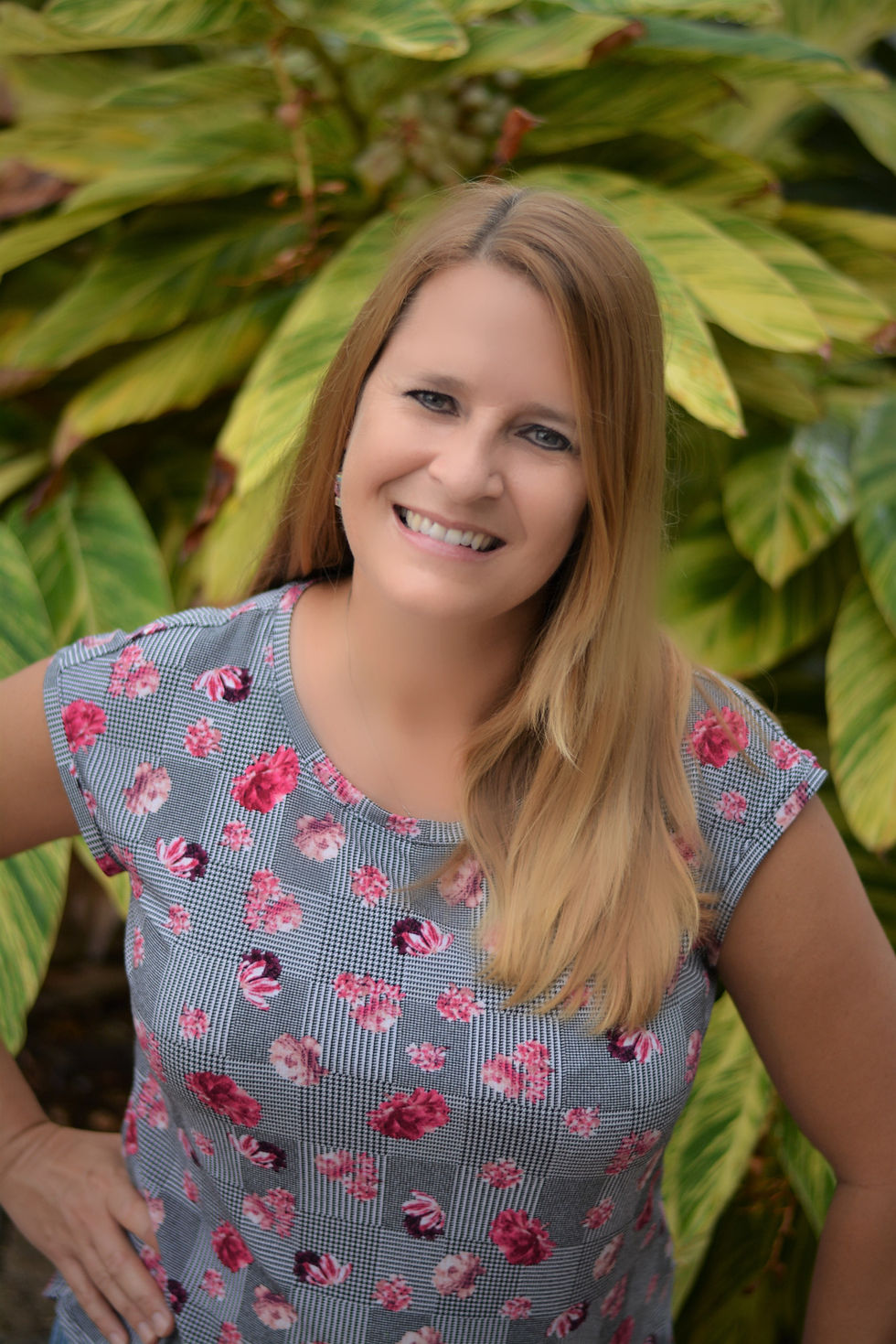Portrait headshot of Lisa smiling in front of green foliage