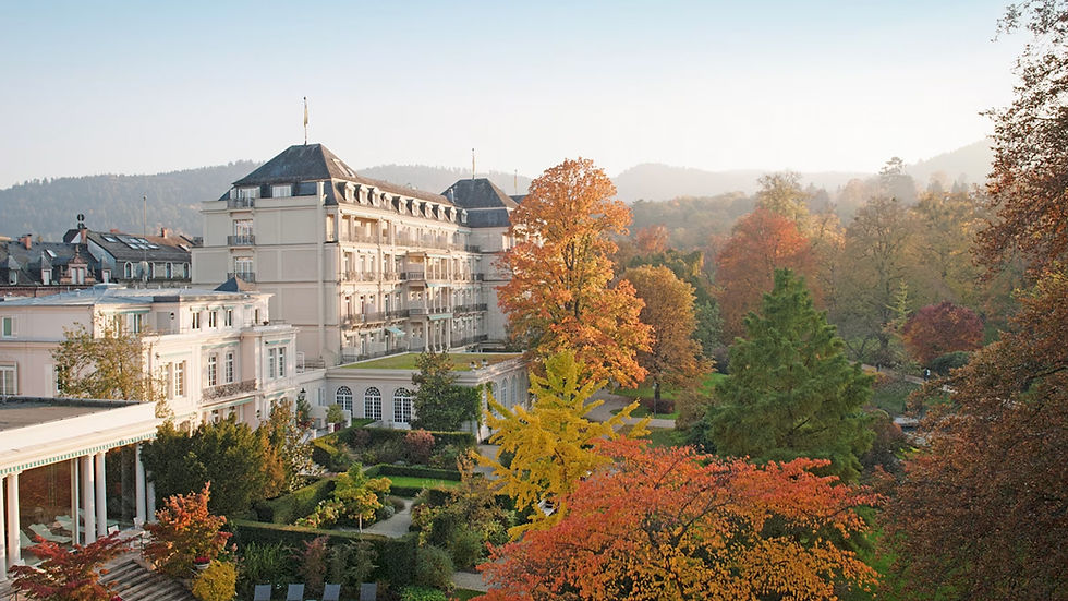 Elegant hotel facade with autumn trees in vibrant red, orange, and green.