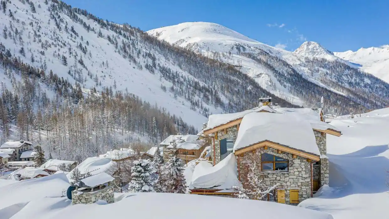 ski chalet covered in snow in front of mountain