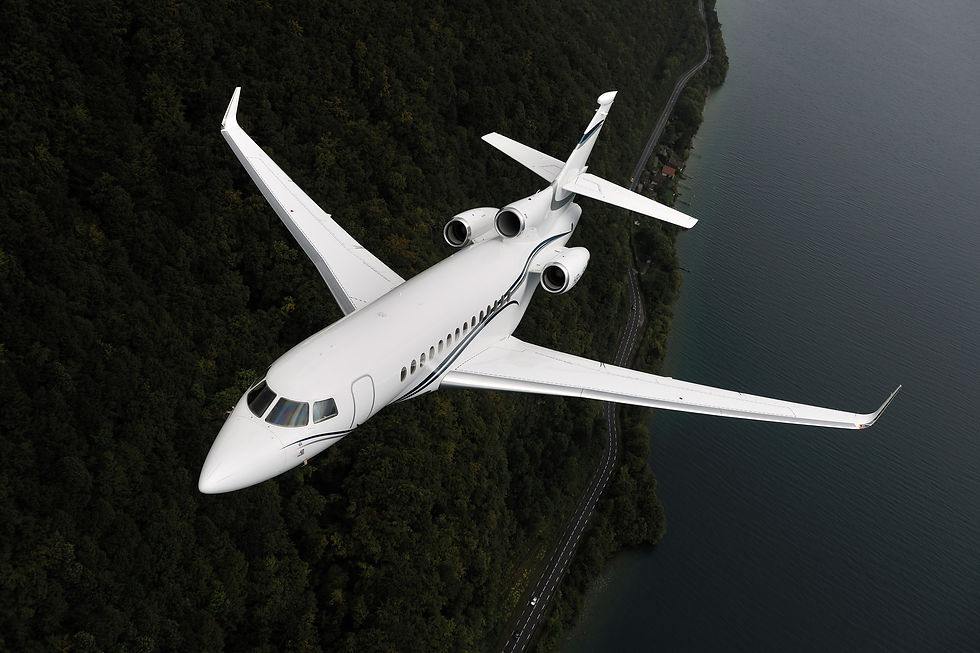 dassault falcon 7X private jet flying over a forested coastline