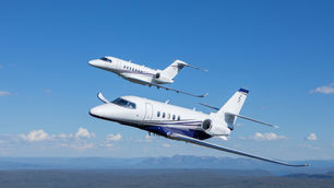 two citation latitude private jets flying over mountains