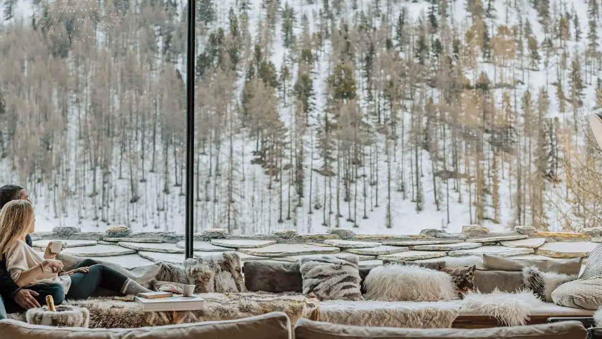 A couple looking out the window towards alpine trees