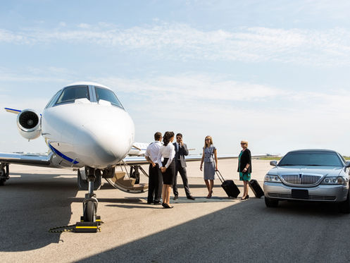 business travellers standing by a private jet and luxury car
