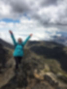 girl standing in victory pose on top of mountain