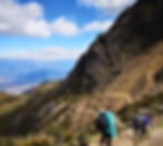 hikers walking down a trail on a mountain