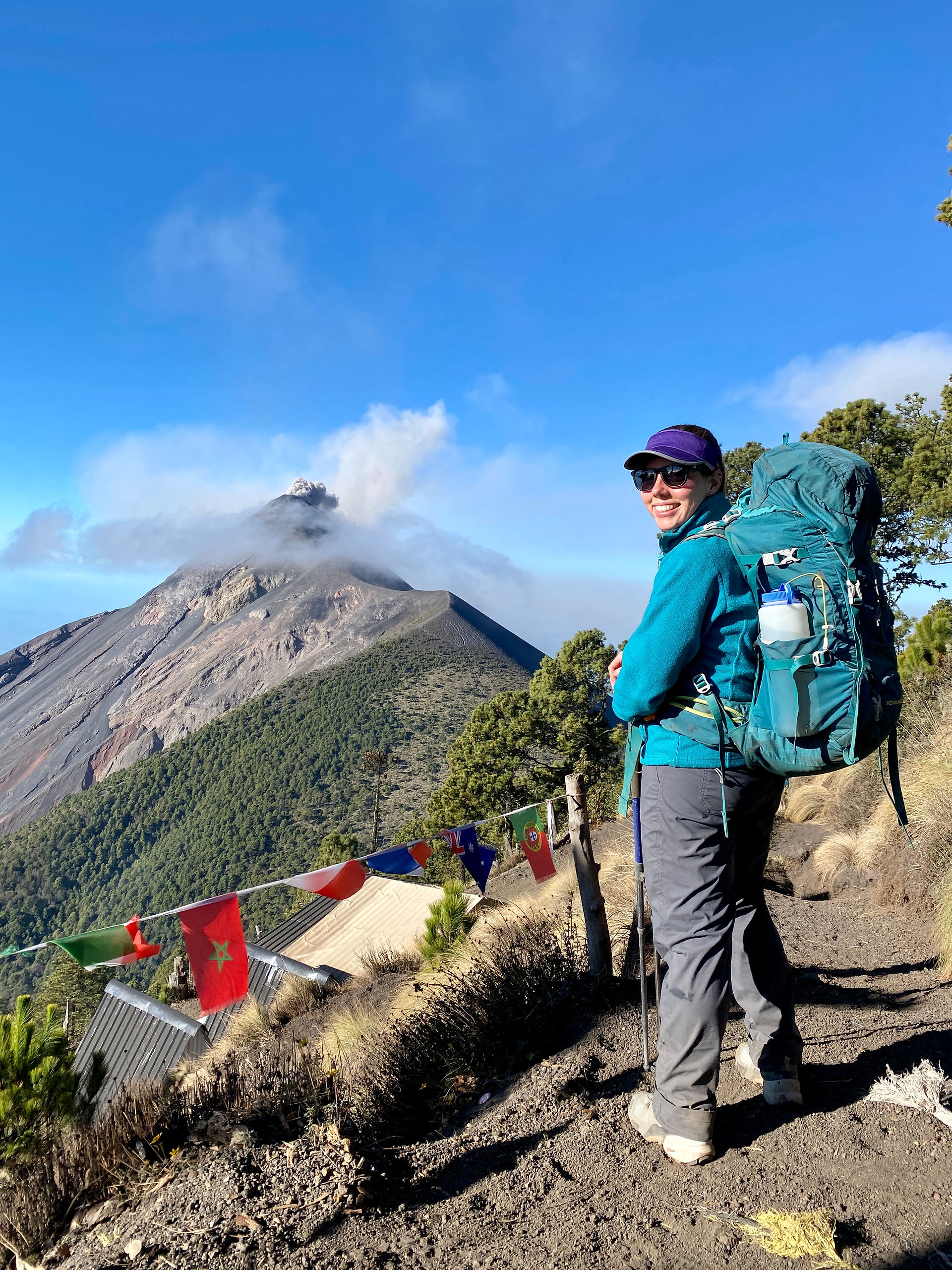 Girl standing on top of mountain with backpack overlooking a volcanoe