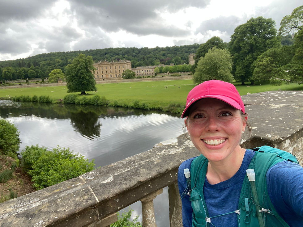 a female runner in a. pink hat smiles and poses in front of a large mansion