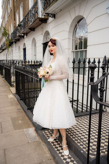 Tiffany in front of a blue door, bride in a vintage dress with flowers by Simon Lycett