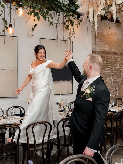A bride walks across chairs at The Hackney
