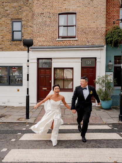 Bride and groom run across a road in central London
