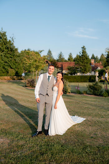 A bride and groom stand in the golden sun 