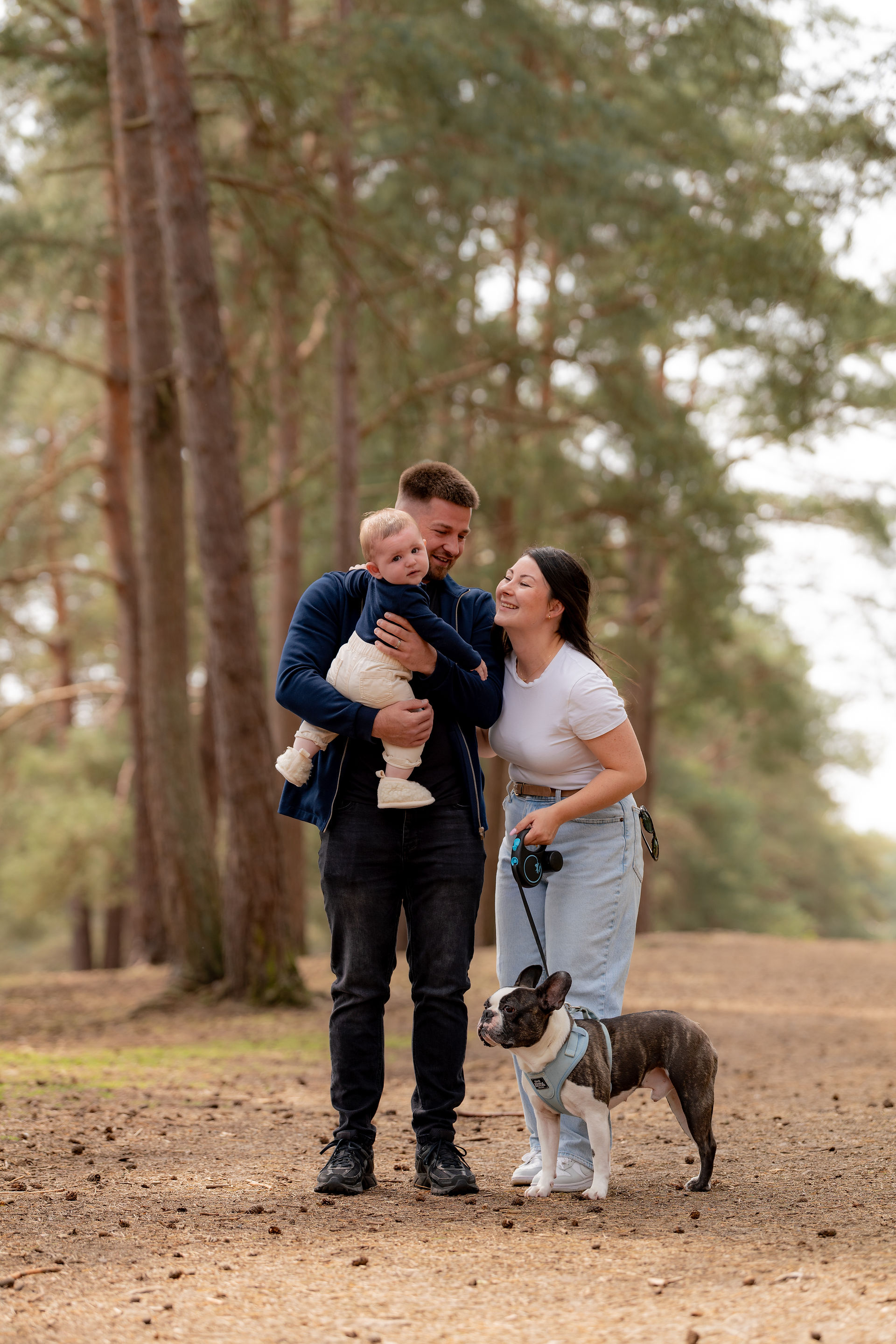 A family with a dog play in the woods