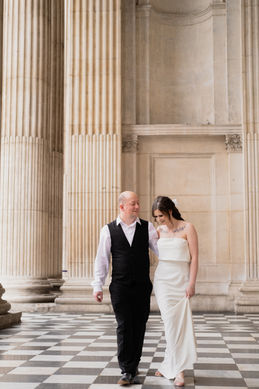 A bride and groom walk over the chequered floor of st Pauls