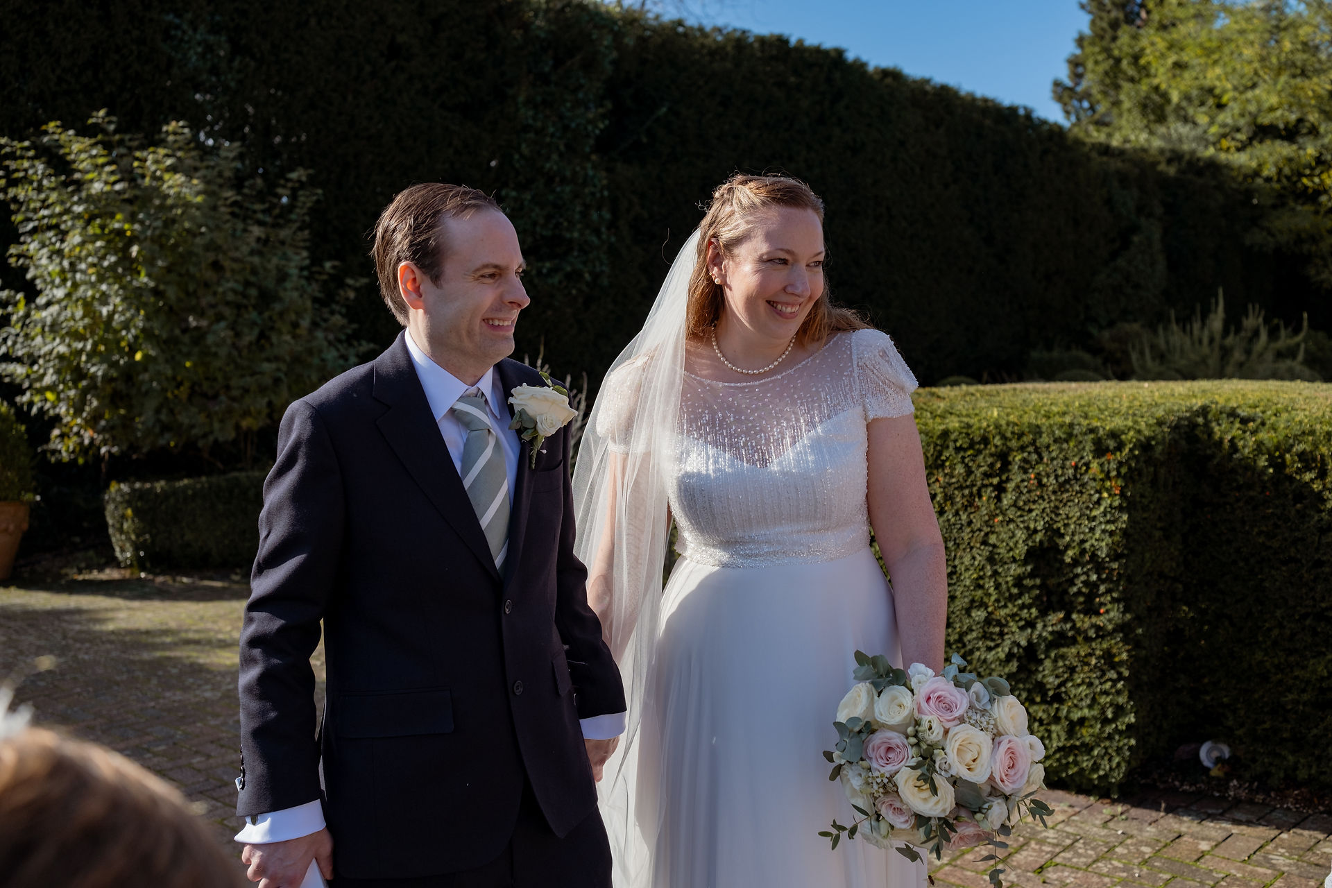 A Bride and Groom hand in hand at their outdoor garden wedding