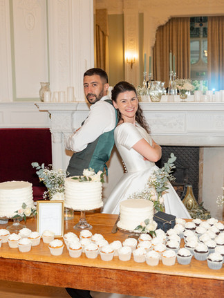 A bride and groom pose in front of their cake