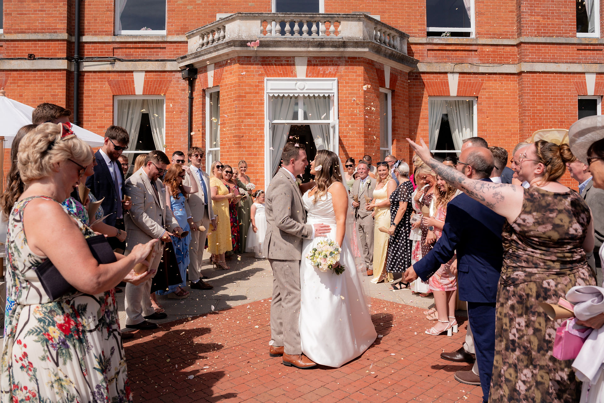 Bride and Groom kiss under confetti at Oakley Hall