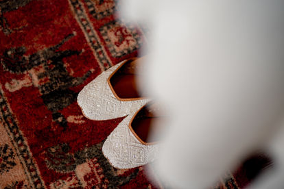 A pair of embroidery shoes sits below a wedding dress